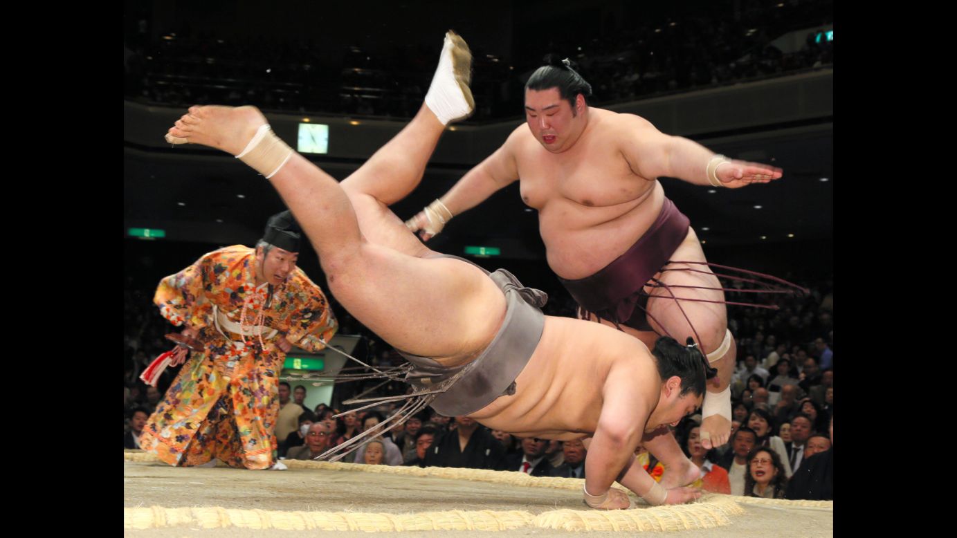 Tokushoryu, right, jumps as his opponent, Okinoumi, falls during a sumo match in Tokyo on Wednesday, January 21.