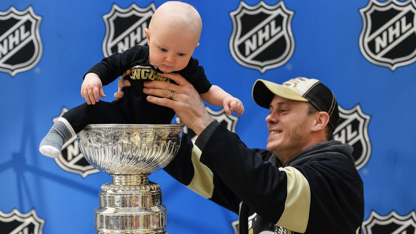 Trevor Young removes his 10-month-old son, Donovan, from the Stanley Cup after posing for a photograph Thursday, January 22, in Columbus, Ohio. The trophy was on display for the fans as part of the NHL's All-Star Weekend.