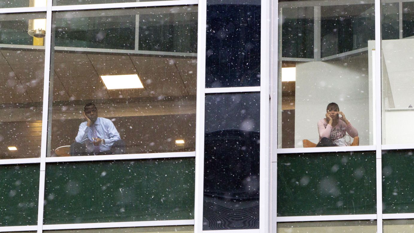 People look out from office building windows as snow falls in downtown Philadelphia on January 26.