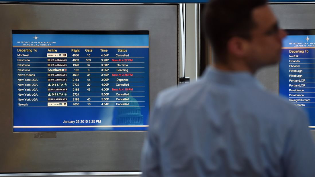 A man stands in front of a screen listing departing flights at Ronald Reagan Washington National Airport on January 26. 