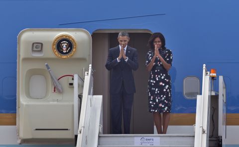 U.S. President Barack Obama and first lady Michelle Obama fold their hands together in a traditional Indian greeting gesture as they prepare to board Air Force One to depart New Delhi on Tuesday, January 27.