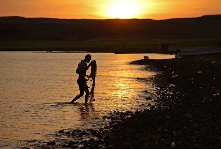 A fisherman from the El Molo tribe walks ashore as the sun rises over Komote, a village on the banks of Lake Turkana, Kenya, near the location of the new wind farm.