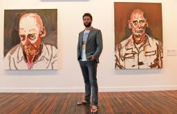 Artist Ben Quilty standing in front of some of his paintings of soldiers in a Sydney art gallery, February 2013.