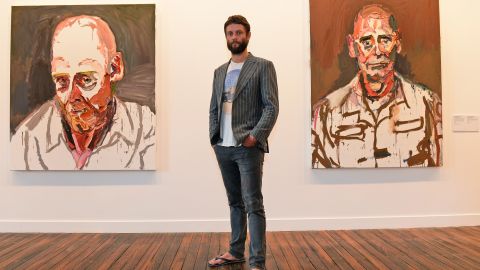 Artist Ben Quilty standing in front of some of his paintings of soldiers in a Sydney art gallery, February 2013.