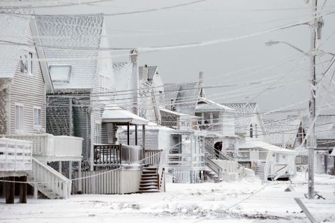 Dexter Newcomb begins cleanup at his house in Scituate, Massachusetts, on Wednesday, January 28, a day after a winter storm left his neighborhood coated in frozen sea spray and sand.