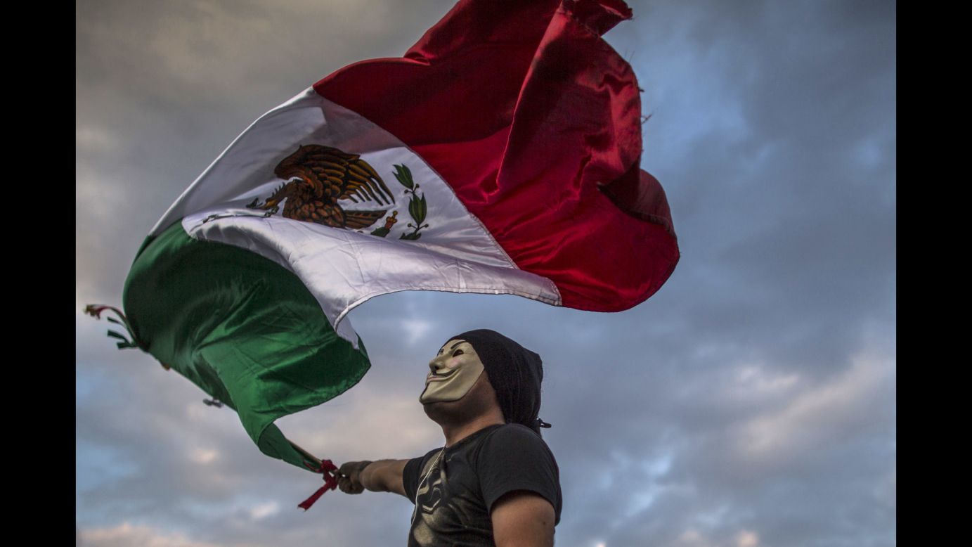 A masked protester waves a Mexican national flag during protests in Mexico City on January 26.