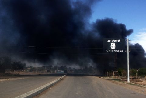 Smoke billows behind an ISIS sign during an Iraqi military operation to regain control of the town of Sadiyah, about 95 kilometers (60 miles) north of Baghdad, on Tuesday, November 25.