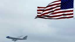 Air Force One flies past an American Flag on its way into Daytona International Airport in Daytona Beach, Florida, in 2004.