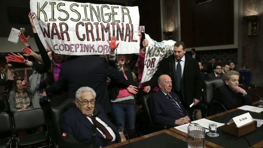 WASHINGTON, DC - JANUARY 29: Protesters shout "Arrest Henry Kissinger for war crimes" as (L-R) Former U.S. Secretary of State Henry Kissinger; former U.S. Secretary of State George Shultz and and former U.S. Secretary of State Madeleine Albright wait to testify before the Senate Armed Services Committee January 29, 2015 in Washington, DC. The committee heard testimony from Kissinger, Schultz and Albright on the topic of global challenges and U.S. national security strategy.