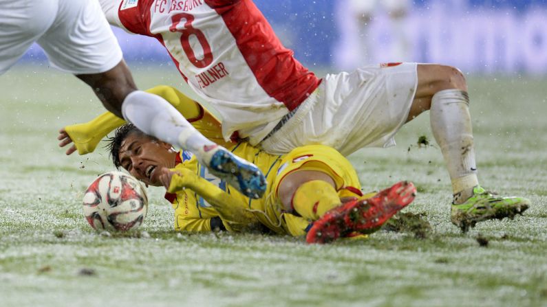 Hoffenheim midfielder Roberto Firmino, bottom, collides with Augsburg's Markus Feulner during a Bundesliga match Sunday, February 1, in Augsburg, Germany.<br />Augsburg won 3-1 in snowy conditions.