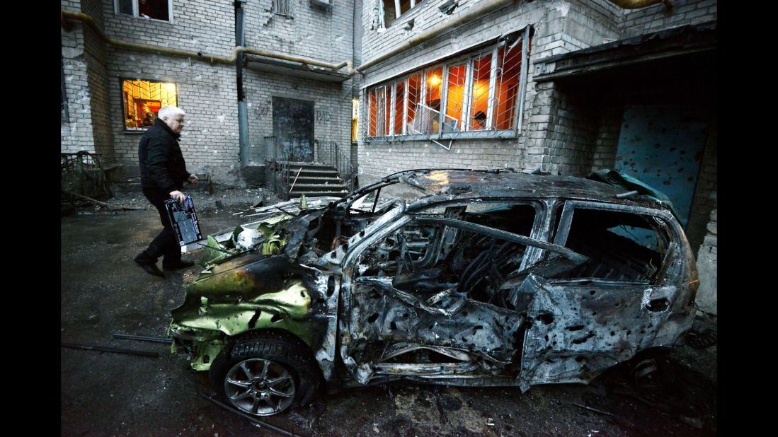 A man stands next to his car in Donetsk on Sunday, February 1, after it was destroyed by shelling.