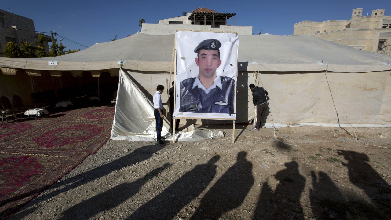 A banner with a picture of al-Kasasbeh is raised by workers near a tent in Amman on Friday, January 30.