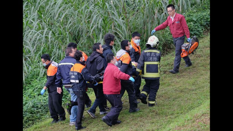 Rescuers carry an injured passenger on a stretcher up the riverbank on February 4.