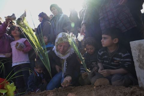 A Kurdish woman kneels beside the burial ground of her husband on Tuesday, February 3.