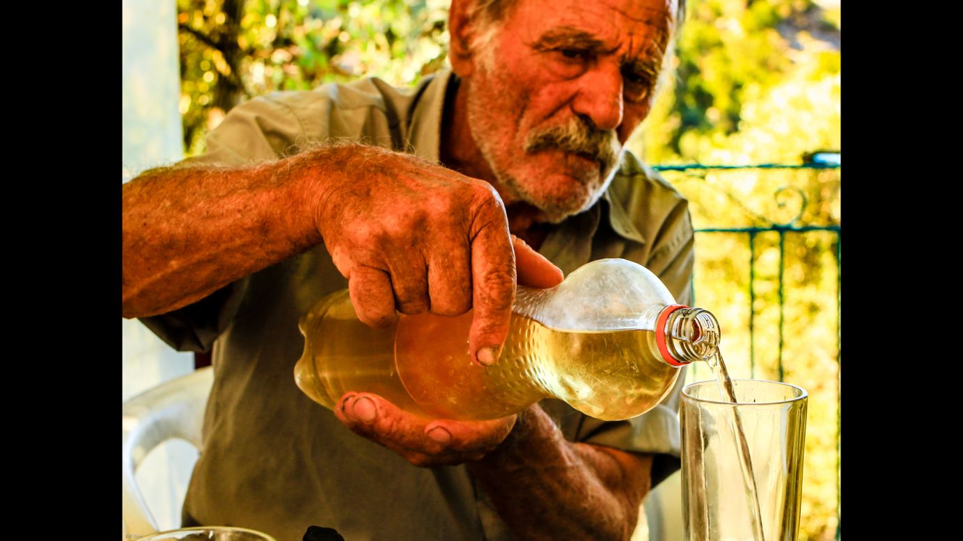 Alexandro Koufadakis, 84, pours a lunchtime glass of homemade wine.