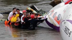Rescue personnel (in helmets) help passengers as they wait to be transported to land from the wreckage of a TransAsia ATR 72-600 turboprop plane that crash-landed into the Keelung river outside Taiwan's capital Taipei in New Taipei City on February 4, 2015. At least 16 people were killed when TransAsia Aiways Flight GE235 with 58 people on board clipped a road bridge and plunged into the river in Taiwan, in the airline's second crash in just seven months. AFP PHOTO / SAM YEH (Photo credit should read SAM YEH/AFP/Getty Images)
