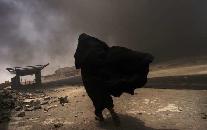 An Iraqi woman walks through a plume of smoke rising from a massive fire at a liquid gas factory as she searches for her husband in the vicinity of the fire in Basra, Iraq, May 26, 2003.  The fire was allegedly started by looters picking through the factory, and residents in the vicinity feared the explosion of the four liquid gas tanks on the premisis.   Weeks after the end of the war, looting continues to be one of the main problems for both Basra and Bagdad cities as coalition forces struggle to get life back to normal.