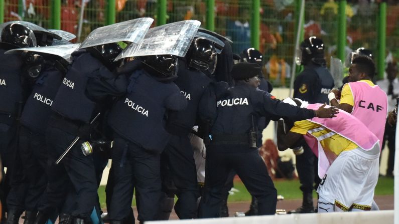 Ghana players leave the pitch protected by riot police at halftime.