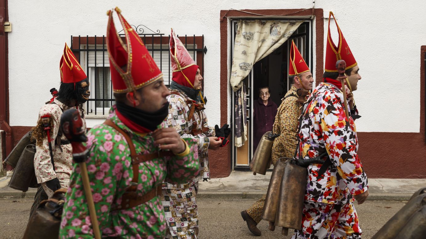 A woman watches members of the Endiablada brotherhood as they march by her home Tuesday, February 3, during the traditional Endiablada festival in Almonacid Del Marquesado, Spain. During <a href="http://www.laendiablada.com/history.php" target="_blank" target="_blank">the festival,</a> men from the town dress up as devil-type characters in colorful jumpsuits and red miter hats.
