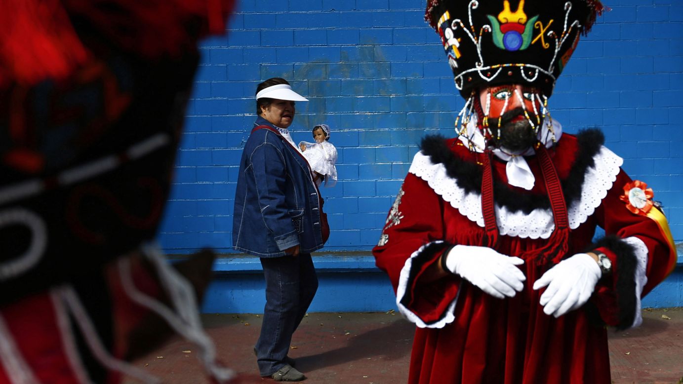 A Chinelo dancer stands in Xochimilco, a borough of Mexico City, as a woman walks past with a dressed-up doll representing baby Jesus on Monday, February 2. This took place during an anniversary celebration marking the 40th day after Jesus' birth.