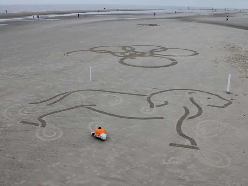 The robot's bulbous balloon wheels allow it to traverse the entire sandy canvas without leaving tire tracks.