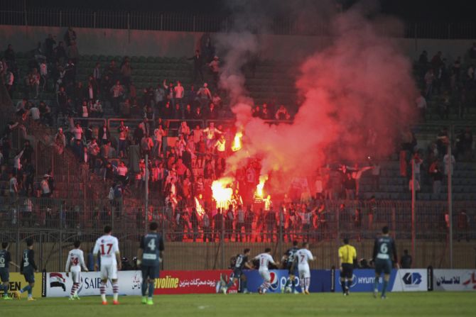 Soccer fans hold flares inside the stadium. The match went ahead despite the violence outside.