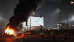 A pickup truck bursts into flames outside the stadium.