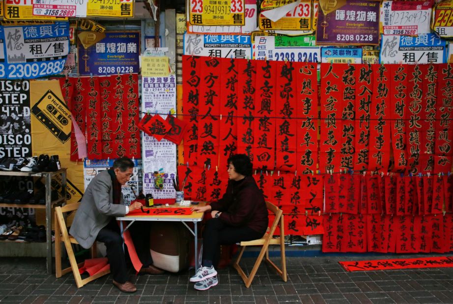A calligrapher, left, writes auspicious characters on red paper to celebrate the  Lunar New Year in Hong Kong on Wednesday, February 4. 