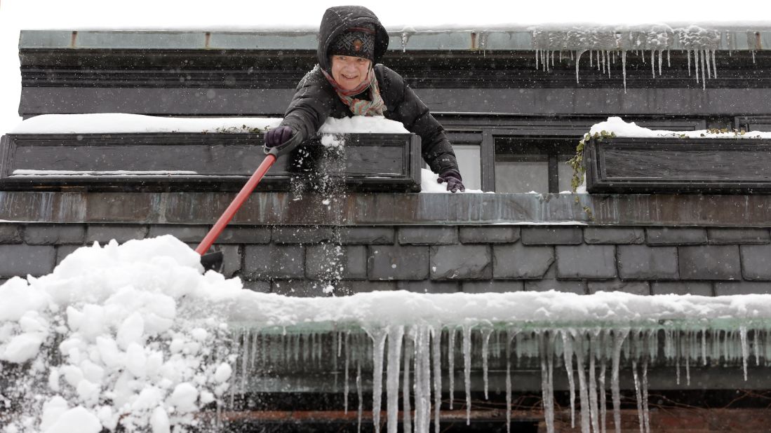 Susan Hartnett shovels snow from the roof of her Beacon Hill home in Boston on February 9.