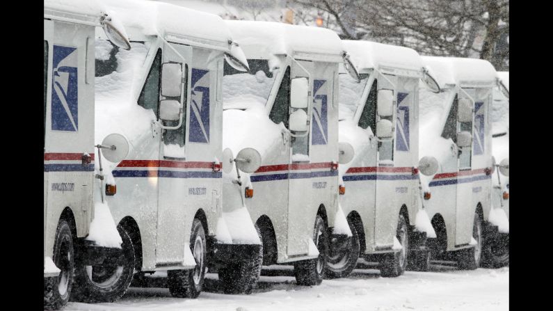 Snow-covered U.S. Postal Service vehicles sit idle February 9 in Marlborough, Massachusetts.