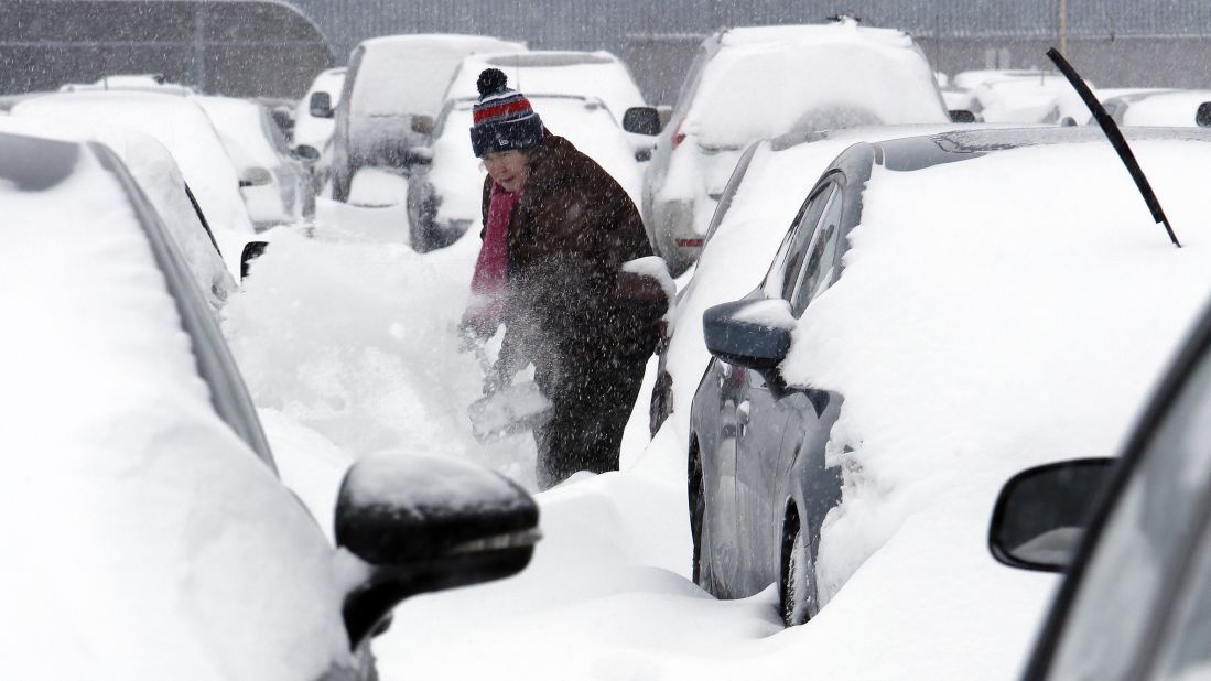 A woman works to dig her car out of the long-term parking lot at the airport in Manchester, New Hampshire, on February 9.