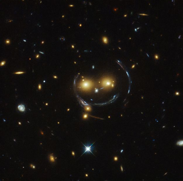 A massive galaxy cluster known as SDSS J1038+4849 <a href="http://www.cnn.com/2015/02/10/tech/space-smiley-face/index.html">looks like a smiley face</a> in an image captured by the Hubble Telescope. The two glowing eyes are actually two distant galaxies. And what of the smile and the round face? That's a result of what astronomers call "strong gravitational lensing." That happens because the gravitational pull between the two galaxy clusters is so strong it distorts time and space around them.