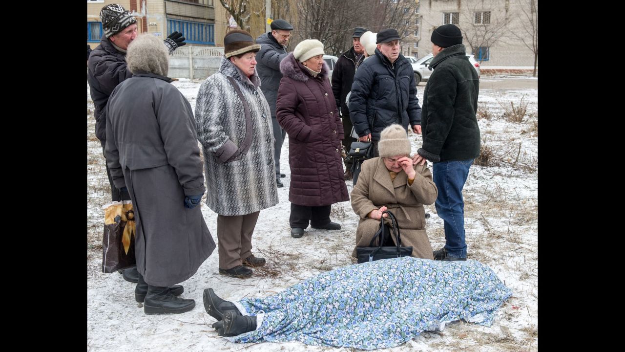 People stand beside the body of a woman killed during shelling in Kramatorsk, Ukraine, on Tuesday, February 10. 