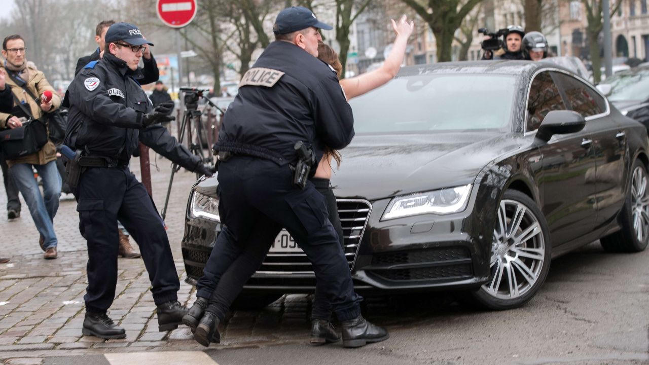 Police detain a topless Femen activist who jumped on the car carrying former IMF chief Dominique Strauss-Kahn (not seen) upon his arrival for his trial in Lille, northern France, on February 10, 2015. Three topless women from the protest group Femen jumped on the car of Dominique Strauss-Kahn as the former IMF chief arrived to testify at his trial for "aggravated pimping." With slogans scrawled on their half-naked bodies and hurling insults at the car, the three protesters were quickly rounded up by police as the car entered an underground parking area. AFP PHOTO / DENIS CHARLETDENIS CHARLET/AFP/Getty Images