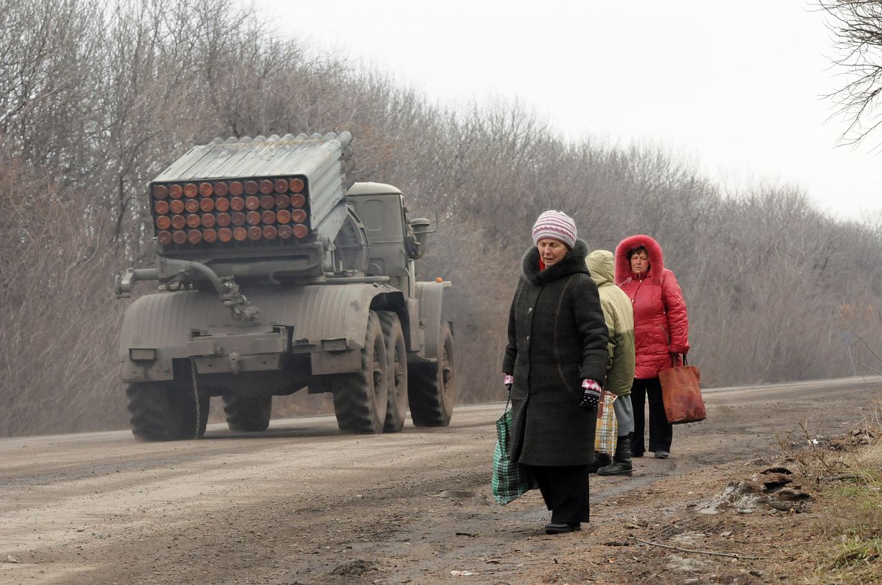 Refugees from Debaltseve escape the fighting while Grad missile systems head to the front on February 5, 2015. Fighting continues between Ukrainian forces and pro-Russian separatists in and around the important rail hub. The humanitarian situation  has become dire as thousands have fled the shelling, while many more are trapped. Residents use all manner of vehicles, driven by volunteers, to get out of the area.