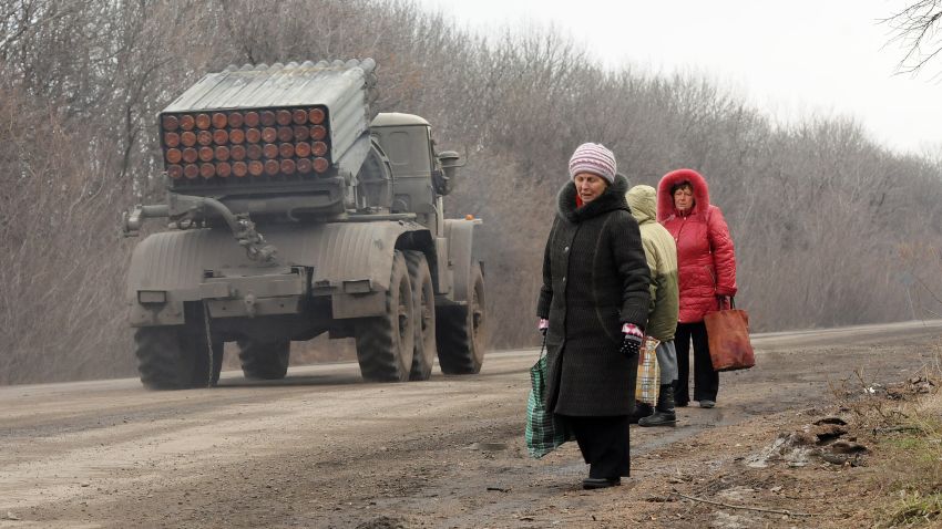 Refugees from Debaltseve are escaping the battle zone on foot while Grad missile systems are heading to the front on February 5, 2015, North of Debalteve, Donbass Oblast, Ukraine. Fighting continues between Ukrainian forces and pro-Russian separatists in and around the important rail ray hub of Debalteve. The humanitarian situation in the town has become catastrophic as thousands have fled, while many more are trapped in the heavily shelled town. Locals each day try to flee the battle zone using cars, trucks or buses driven by volunteers making the round trip multiple times a day.