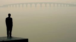 A man looks towards a bridge in heavy fog on December 14, 2004 in Beijing, China. The bad weather has made it harder for Beijing to achieve the target of 18 clear-sky days in December, laid out by the environmental protection campaign, which requires the capital to have clear sky for 62 percent of the year, equivalent to 227 days. Beijing has pledged to cleanse the skies before the 2008 Olympic Games. (Photo by Guang Niu/Getty Images)