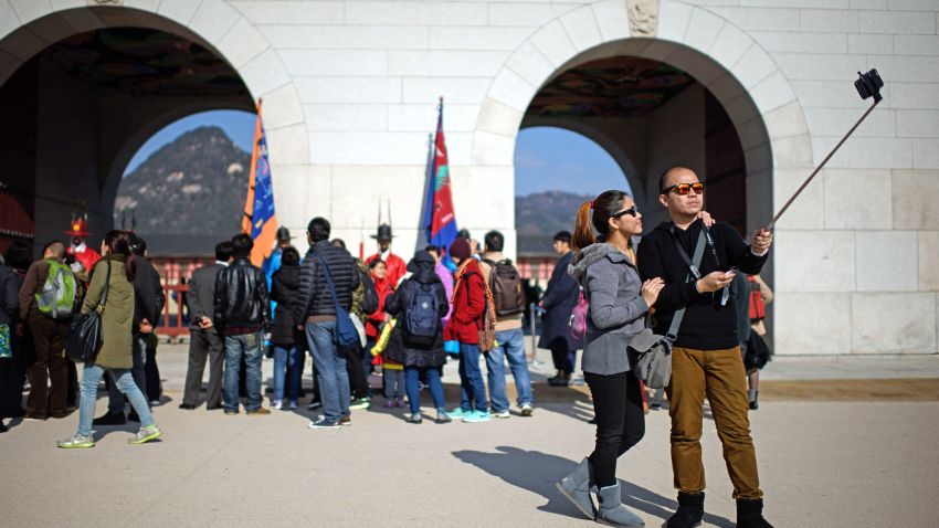 In a photo taken on November 26, 2014 a couple use a 'selfie stick' to take a photo before the Gyeongbokgung palace in central Seoul. In South Korea anyone selling an unregistered bluetooth-enabled selfie stick could face a 27,000 US dollar fine or up to three years in prison, the Science Ministry announced last week. The focus of the ministerial crackdown are those models that come with bluetooth technology, allowing the user to release the smartphone shutter remotely, rather than using a timer. As such they have to be tested and certified to ensure they don't pose a disruption to other devices using the same radio frequency. AFP PHOTO / Ed Jones        (Photo credit should read ED JONES/AFP/Getty Images)