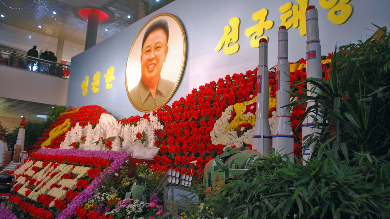 Yep, those are missiles in front of a portrait of Kim Jong Il surrounded by a display of Kimjongilias, the colorful flowers named after him.