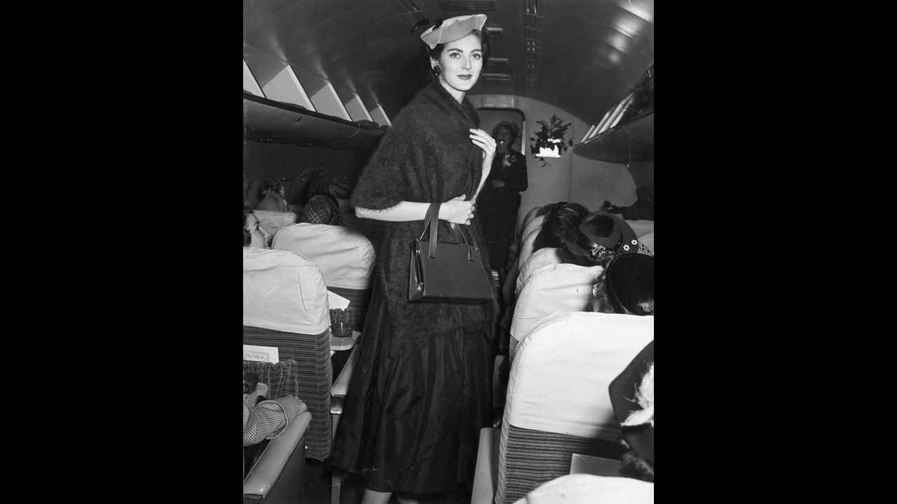 Dell'Orefice wore a hat and a mohair wrap while walking the aisle of an airplane during a 1955 fashion show.