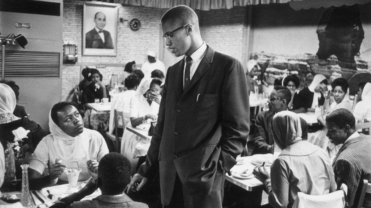 Malcolm X talks to a woman inside a Halal restaurant patronized by black Muslims in Harlem.