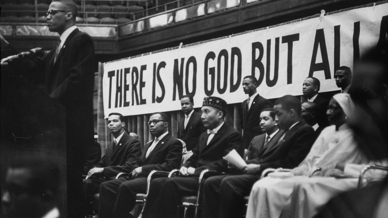 Nation of Islam leader Elijah Muhammad, seated in the hat, listens as Malcolm X speaks at a Nation of Islam convention in Chicago in February 1961. It was Malcolm X who bestowed the title "Honorable" to Muhammad. <br />