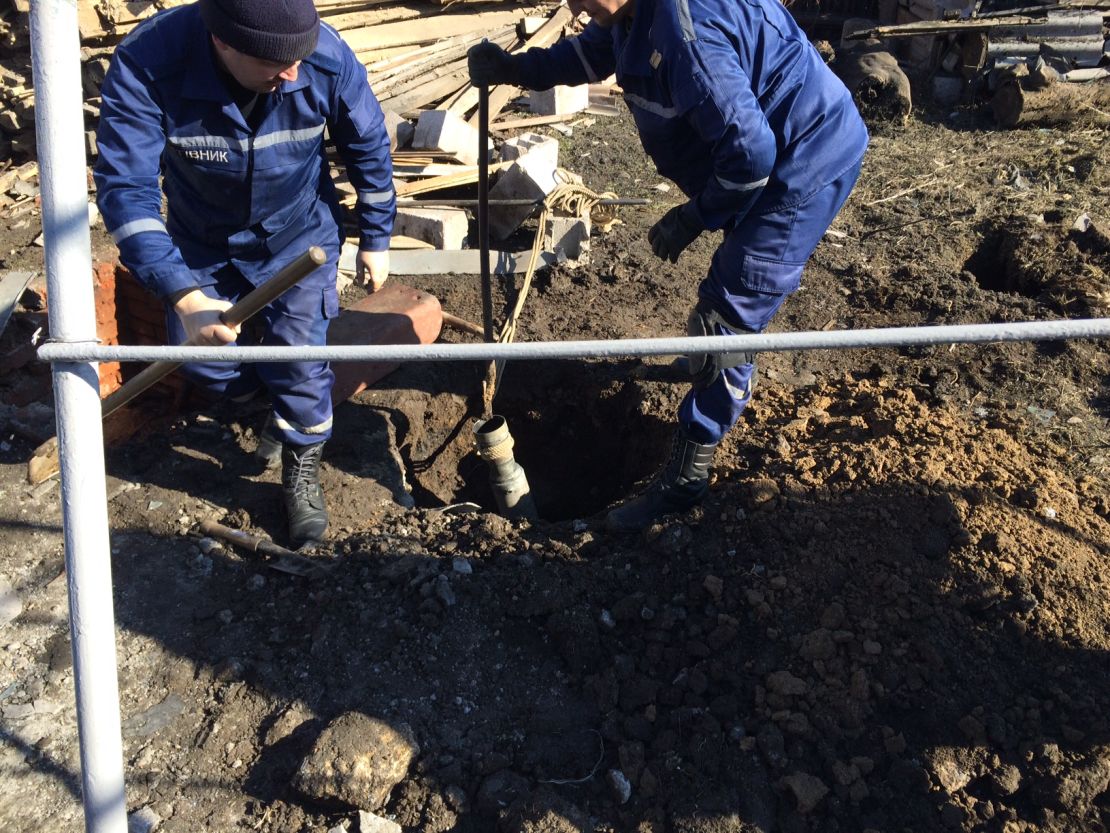 Policemen dig out a rocket in Sartana, a village near Mariupol, on February 14.