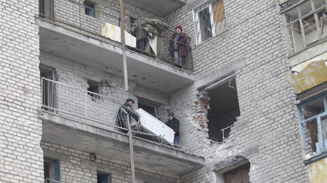 People carry a refrigerator through a balcony at an apartment building that was damaged in recent shelling in Svitlodarsk on February 15.