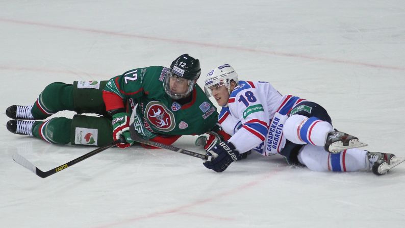 Ak Bars' Mikhail Glukhov, left, and Lada's Georgy Belousov fall to the ice Friday, February 13, during a KHL hockey game in Kazan, Russia.
