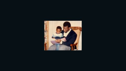 Benjamin Watson sits on his dad's lap while reading a book