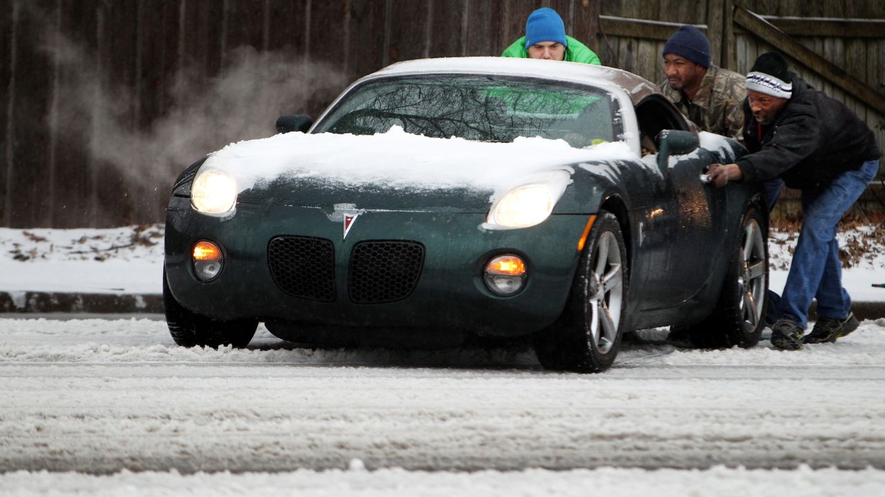Sean Strahn, from left, Kelton Taylor and Tommy Reed help a motorist whose car was stuck in the slushy road conditions in Memphis, Tennessee, on February 16.