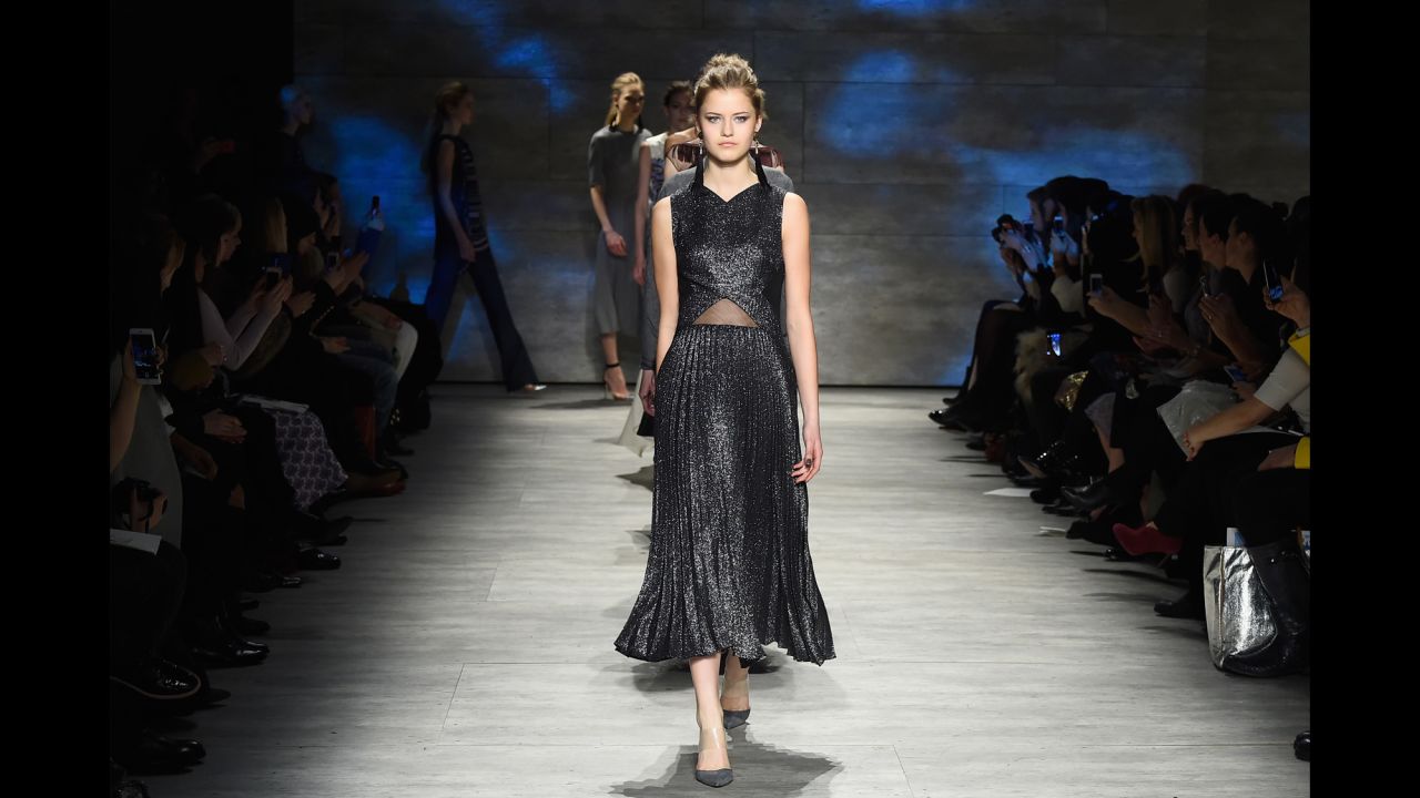 A model walks in a metallic pleated dress with tassel earrings for Lela Rose.