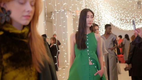 A model poses in a playful, Kelly green pantsuit for Rosie Assoulin.
