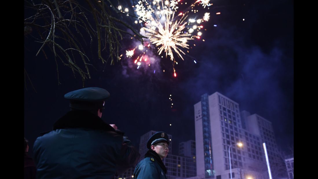 Security guards watch as fireworks go off on the eve of the Lunar New Year in Beijing on Wednesday, February 18.